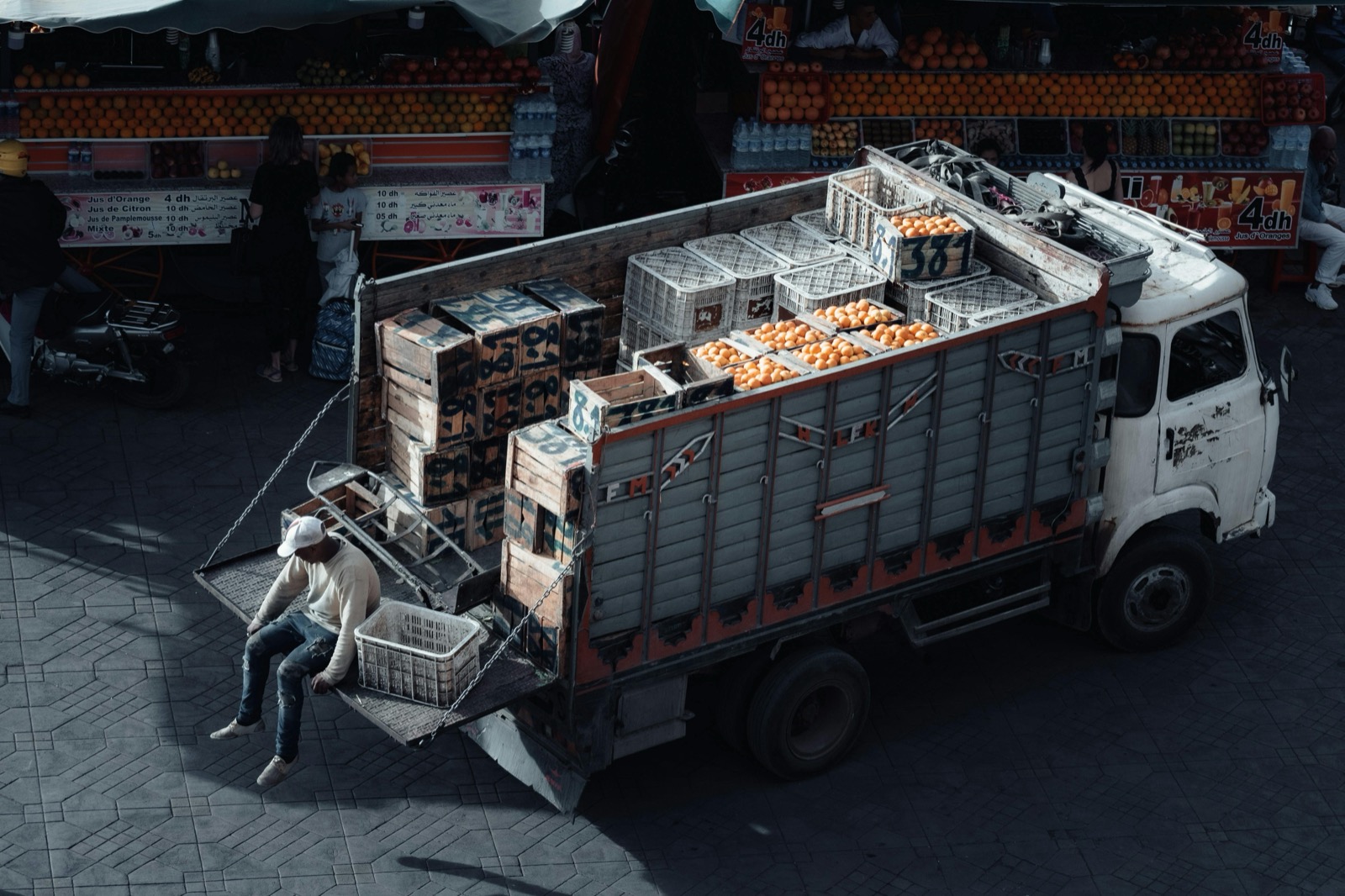 Camión repartiendo cajas de naranjas a puestos de un mercado